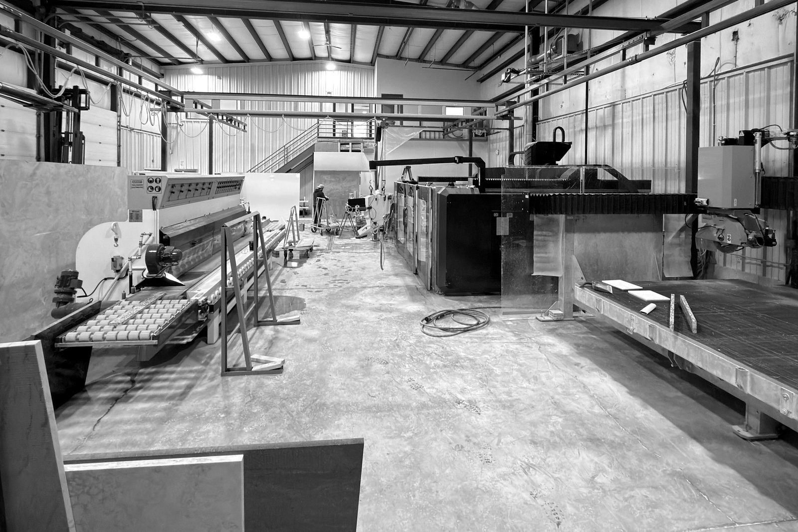 A stone fabrication shop: an edge polisher, a sawjet and a bridge saw under workstation cranes